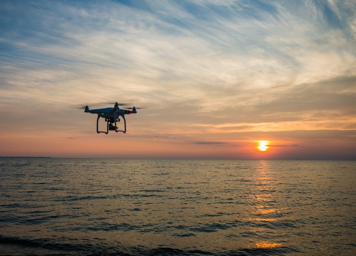 DJI drone flying over the ocean at sunset