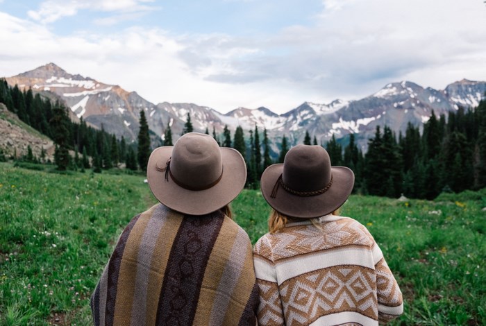 Two women in hats looking at mountains