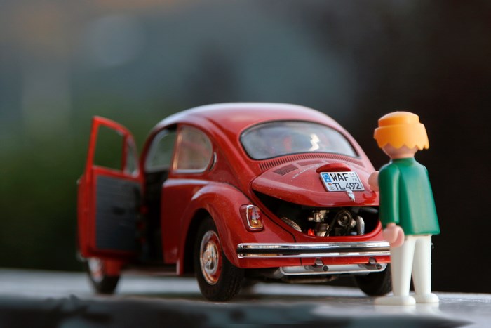 Playmobil figure with a red Volkswagen Beetle toy car