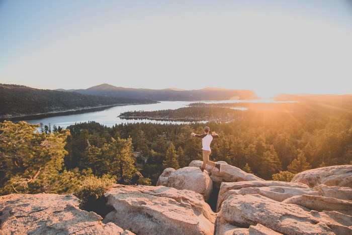 Man jumping on rocks overlooking a lake at sunset