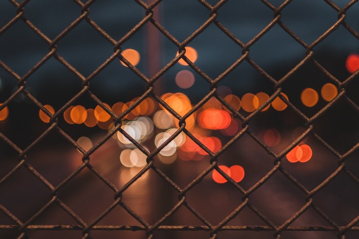 Bokeh lights behind a chain-link fence