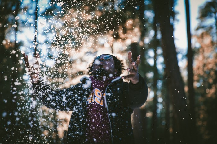 Man throwing snow in a forest