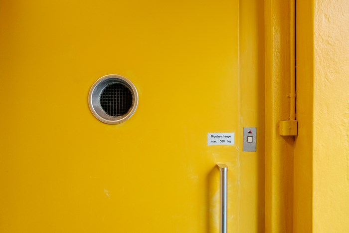 Yellow door with round vent and elevator controls