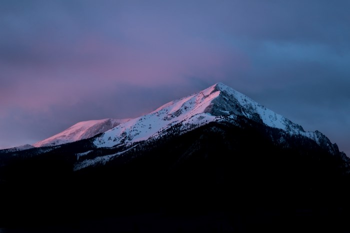 Snow-capped mountain peak at sunrise with pink and blue sky