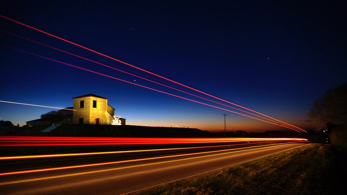 Long exposure of light trails near a building at dusk