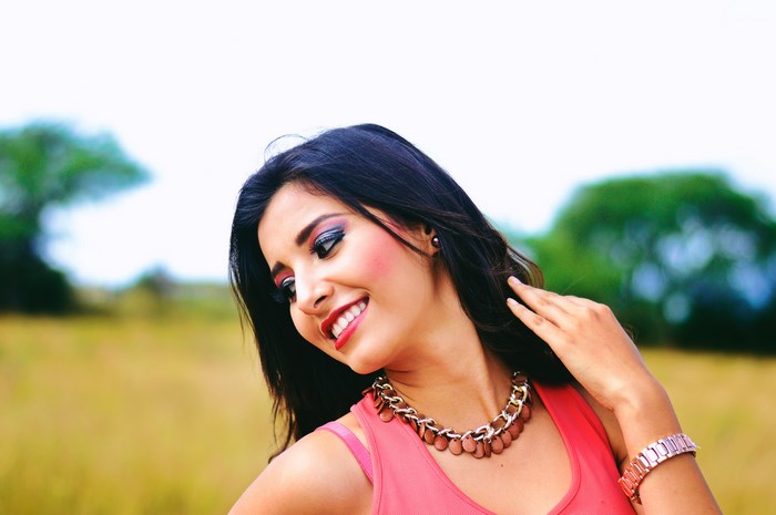 Woman with pink top and jewelry in a field