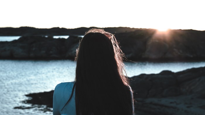 Girl watching the sunset over the water