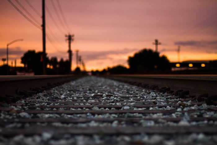 Railway tracks at sunset with power lines