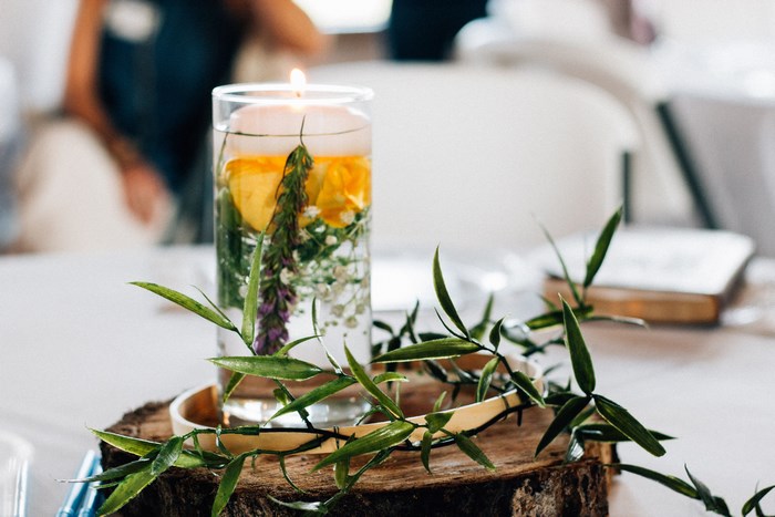 Floating candle with flowers and greenery on a log