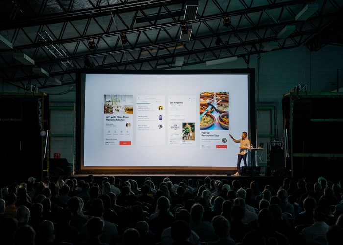 Man presenting Airbnb app design to a large audience
