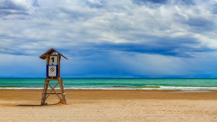 Lifeguard stand on a sandy beach with the ocean and clouds