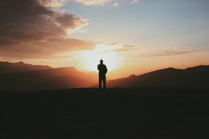 Silhouette of a person standing on a mountain at sunset