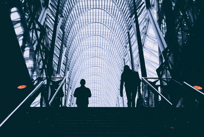 Two people ascend a grand staircase in a modern building