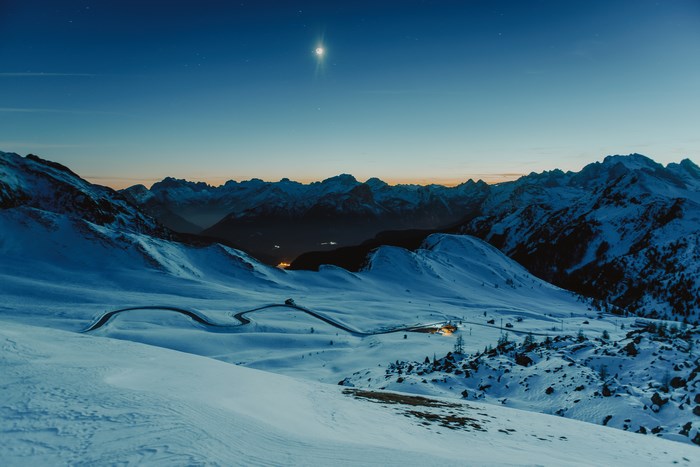 Snowy mountain pass at dusk with moon
