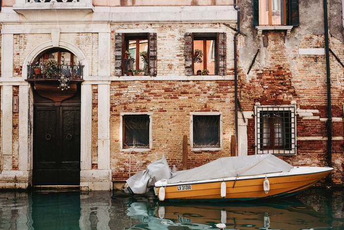 Boat docked by a brick building in a Venice canal