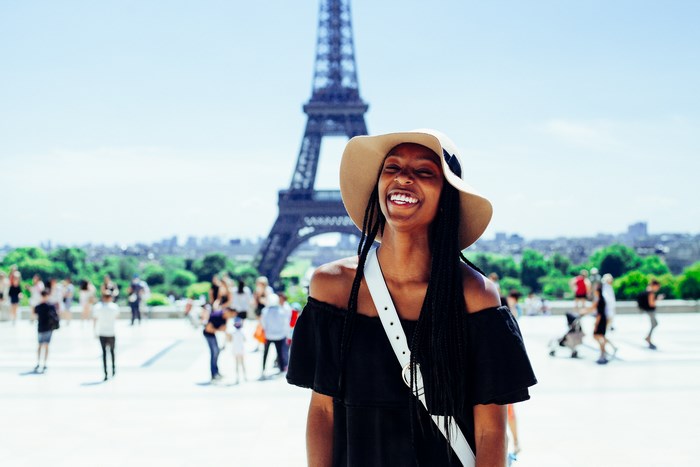 Woman in hat laughing in front of Eiffel Tower, Paris