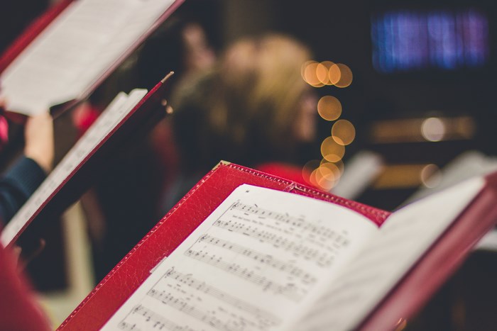 Choir singing from sheet music in red folders