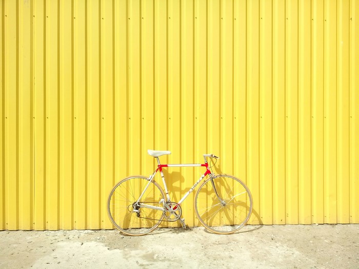 Vintage road bicycle leaning against a yellow corrugated wall