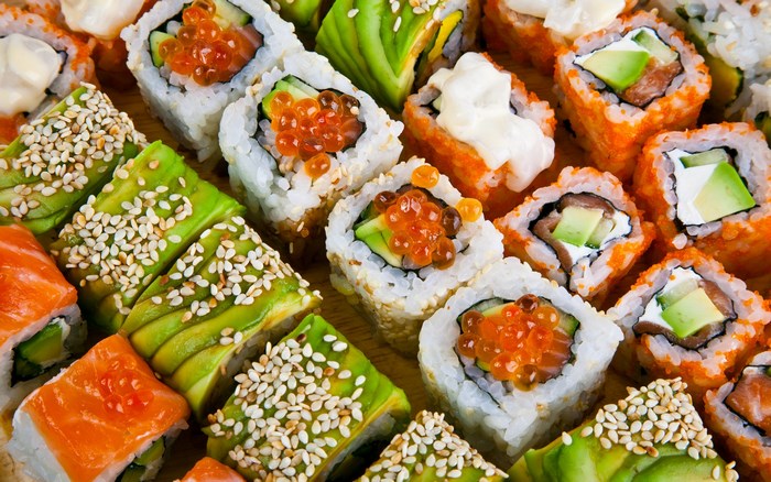 Assortment of sushi rolls with avocado, salmon, and roe