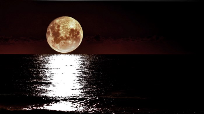 Full moon over the ocean at night