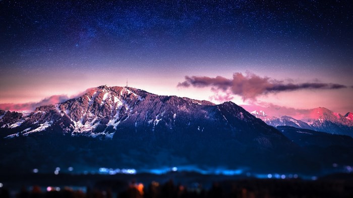 Mountain under starry sky with city lights