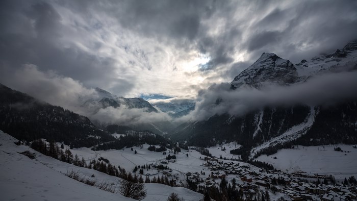 Snowy mountain village under cloudy sky