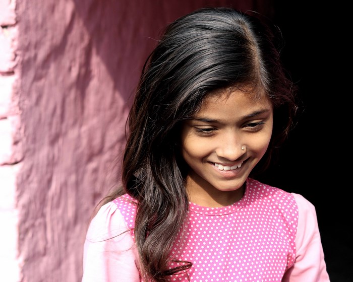 A young Indian girl smiling outdoors