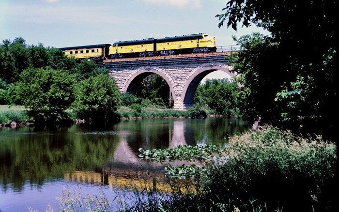 Yellow train on a stone bridge over a river