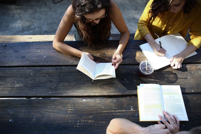 Women studying and reading at a wooden table
