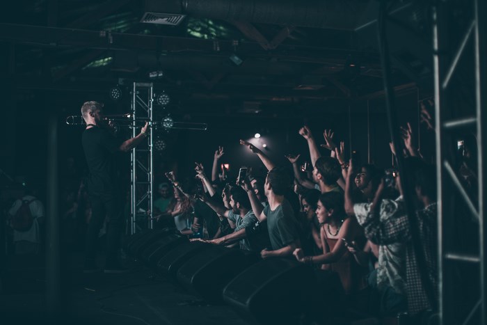 Musician plays trombone for a cheering crowd at a live music event