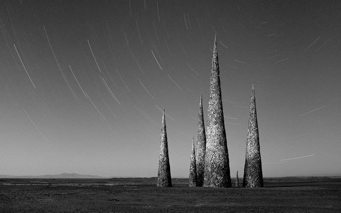 Spiky sculptures in a desert landscape with star trails