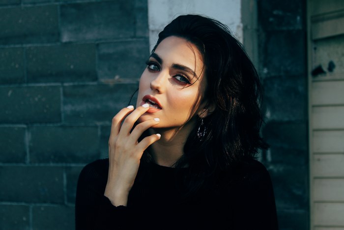 Woman with dark hair posing outdoors