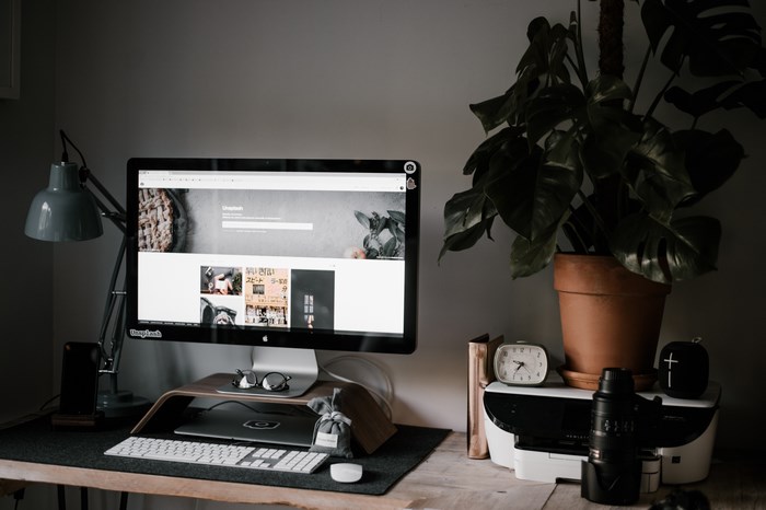 Apple iMac desk setup with plant and camera lens