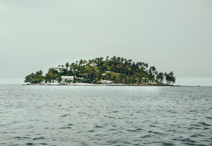 Tropical island with palm trees and white buildings in the ocean