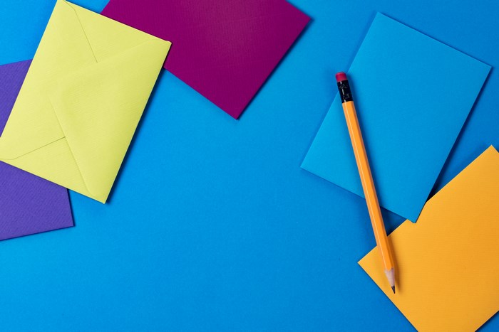 Colorful envelopes and pencil on blue desk