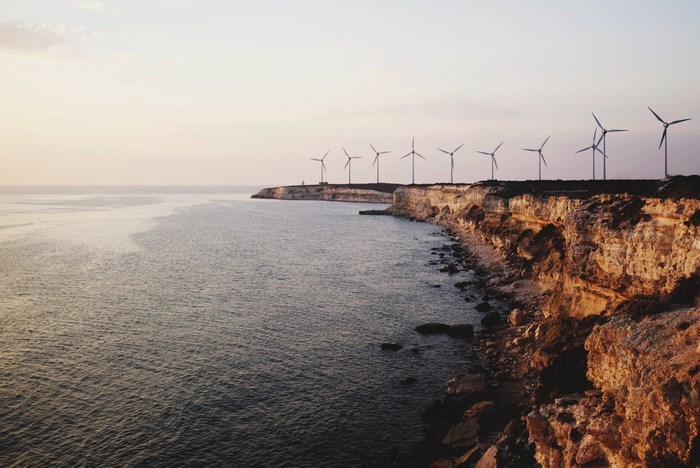 Wind turbines on a cliff overlooking the sea at sunset