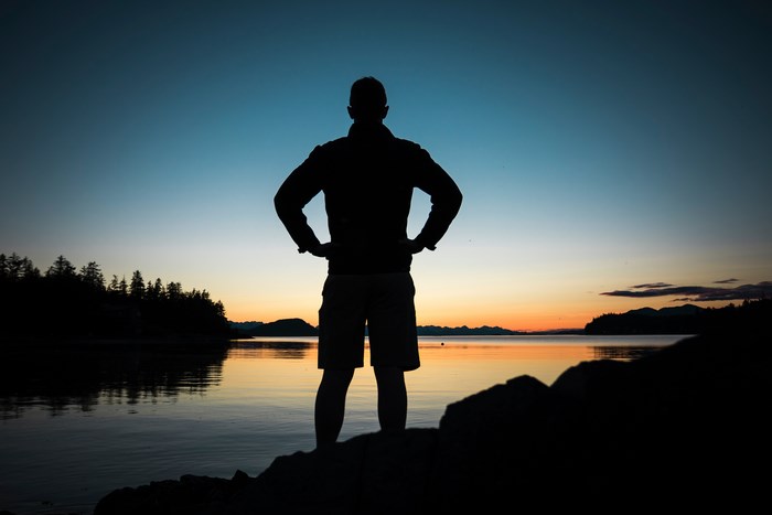 Silhouette of Man Standing by Lake at Sunset
