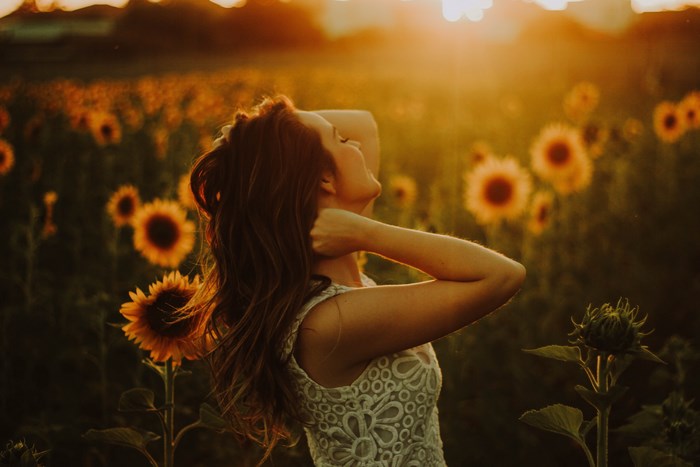 Woman in a sunflower field at sunset