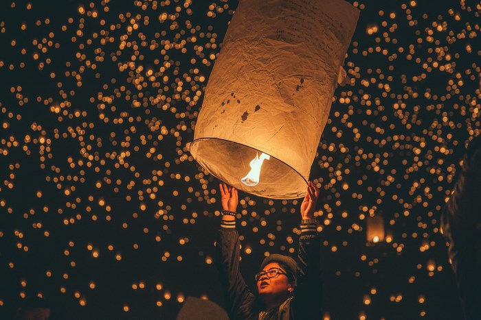 Person holding a lit lantern at night with bokeh lights