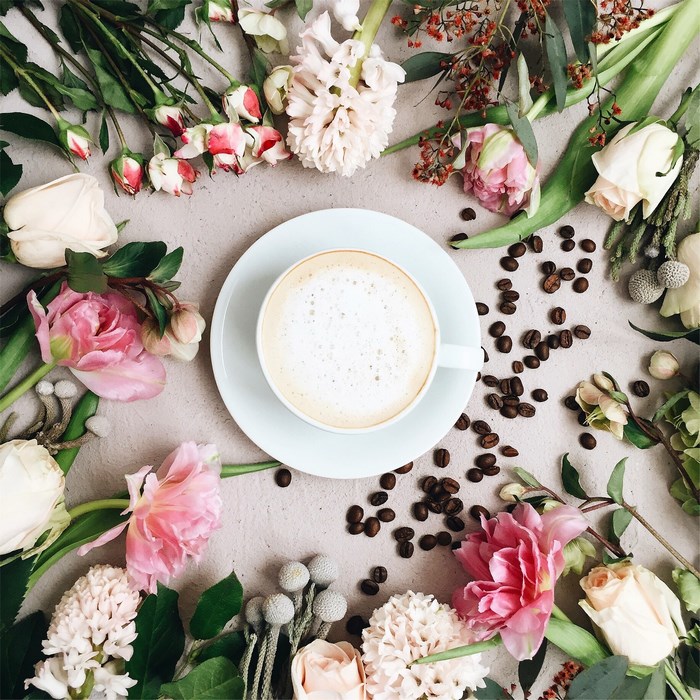 Cup of coffee with flowers and coffee beans flatlay