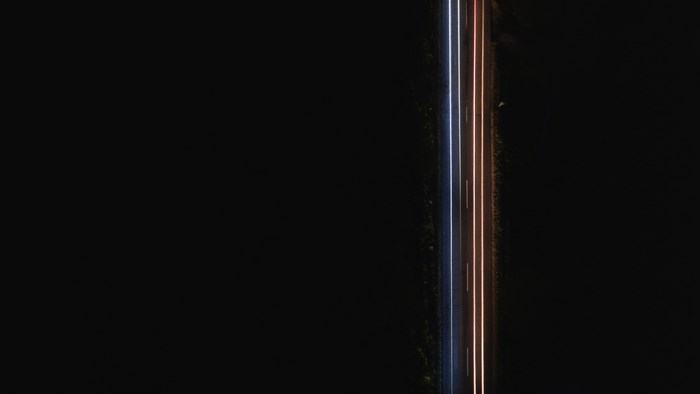 Aerial view of light trails on a dark road at night