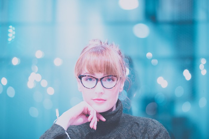 Woman with red hair and glasses in front of bokeh lights