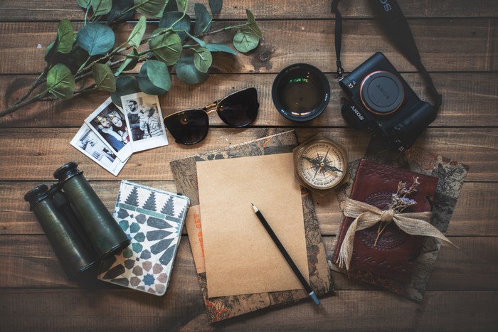 Flatlay of travel items on a wooden table