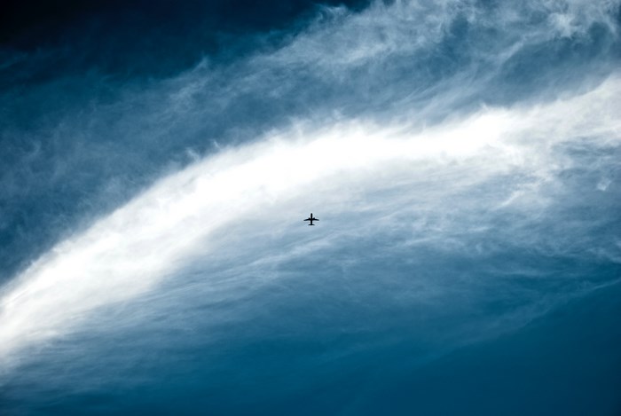 Airplane flying through a cloudy blue sky