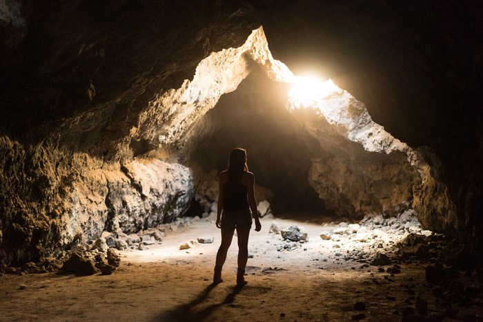 Woman standing in a cave entrance with sunlight