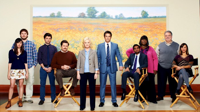 Parks and Recreation cast posing in front of a painting
