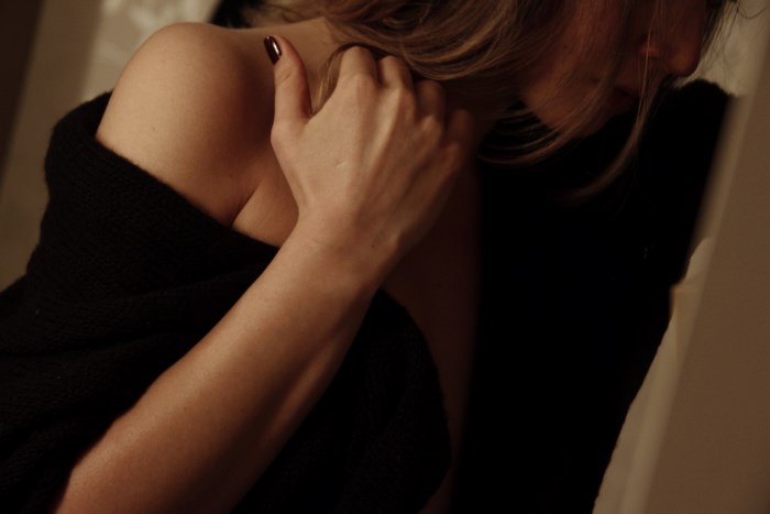 Woman in black sweater with hand on shoulder