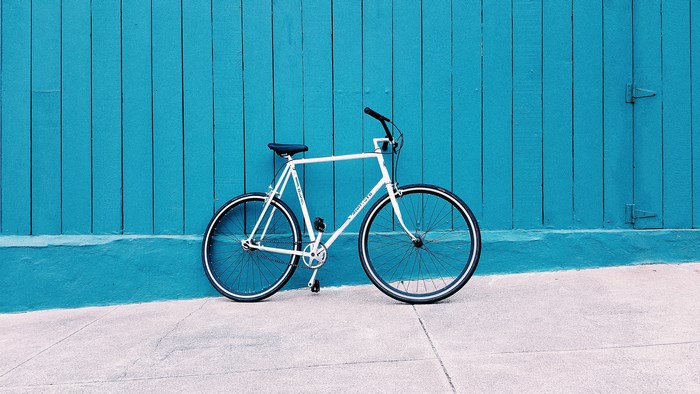 White Bianchi bicycle against a teal wooden wall