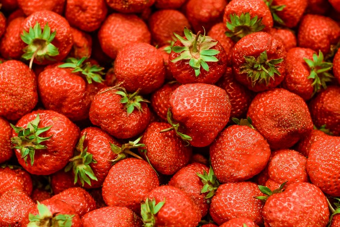 A pile of fresh, red strawberries with green stems
