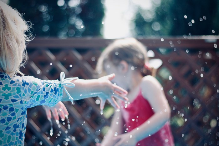 Two girls splashing water in a pool on a summer day